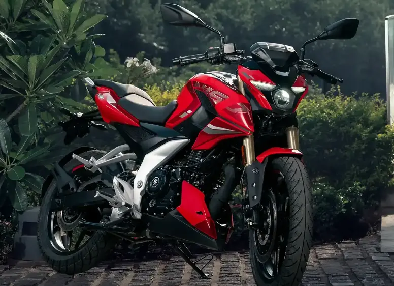 Bajaj Pulsar in red and black color parked near garden and background is full of plants and leaves